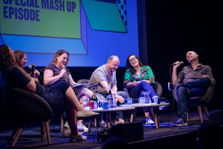 A group of six people sitting on a stage, talking and laughing as part of London Podcast Festival