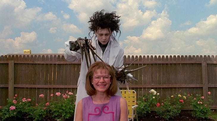 A still from Edward Scissorhands showing Johnny Depp's character appearing to massage a woman's head with his scissorhands