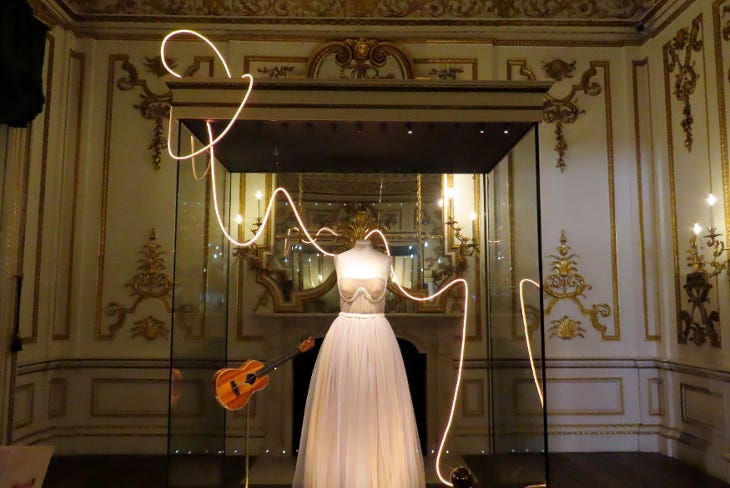 Taylor Swift's dress and guitar on display in a glass case in the V&A