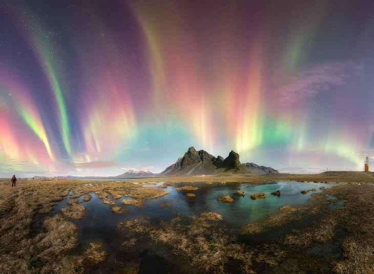 A photograph of the northern lights in the night sky behind a rock formation