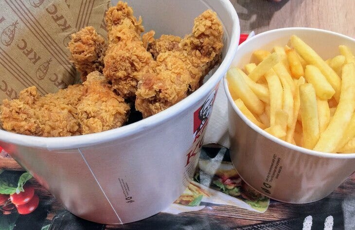 A bucket of dead animal remains in breadcrumbs next to some fries