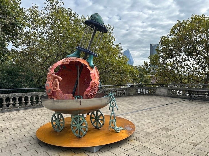 A strange sculpture featuring a melting sphere in what looks like a pram