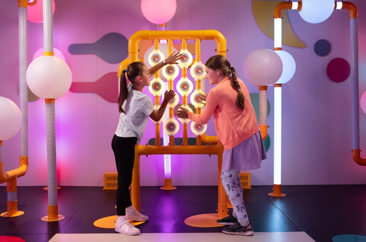 Two children playing with an interactive exhibit inside a colourful museum gallery