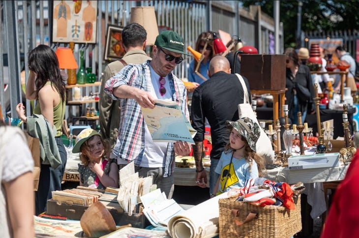 A man and two young girls browsing at a flea market