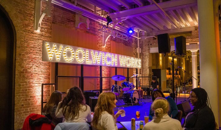 People watching a stage inside Woolwich Works