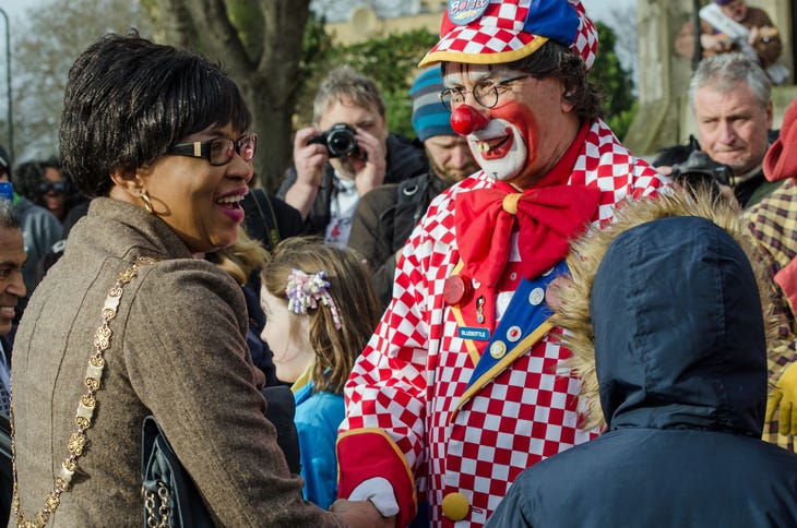 A clown shaking hands with a civilian.