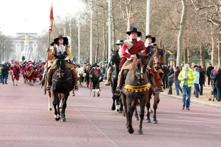 People in royalist costumes riding horses down the Mall