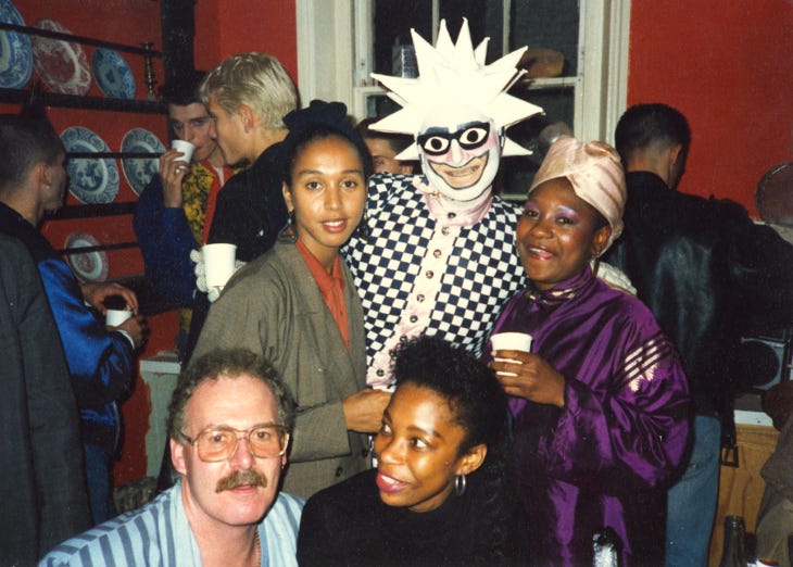 A group of five people at a party, including one in a black and white costume