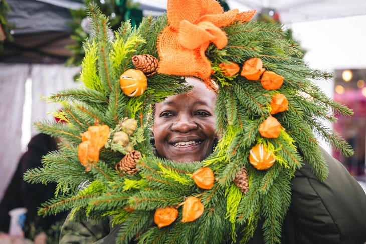 A woman holding a festive wreath up to her face