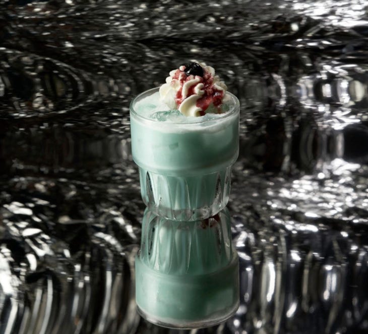 A green cocktail with cream on top