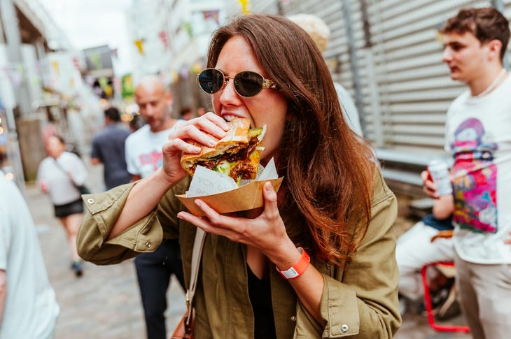 A woman taking a bite of a sandwich