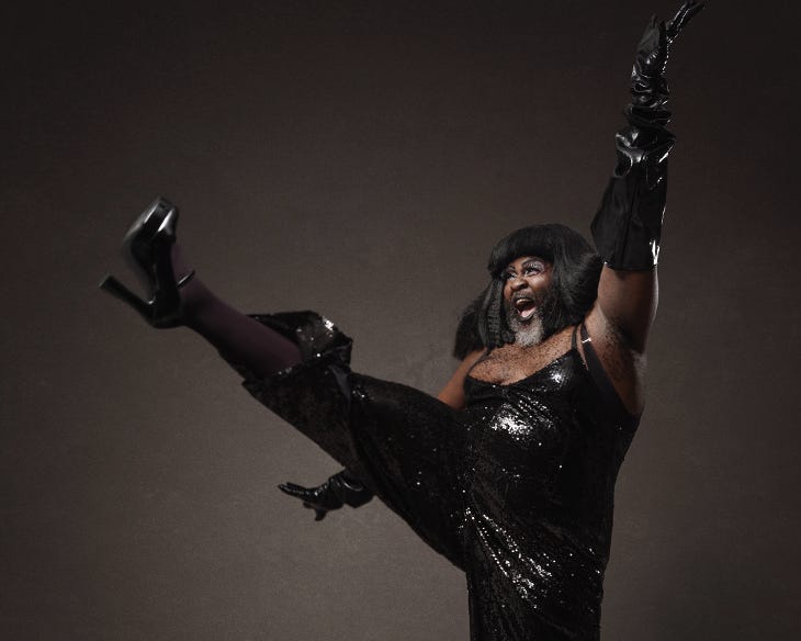 Le Gateau Chocolat dressed in a black sequin outfit performing a high kick