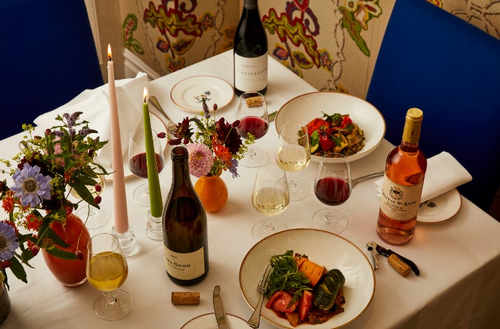 A table laid up for dinner with candles, plates of food and bottles of wine