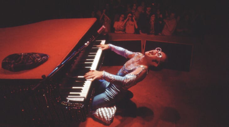 A still from a film of Elton John playing a piano