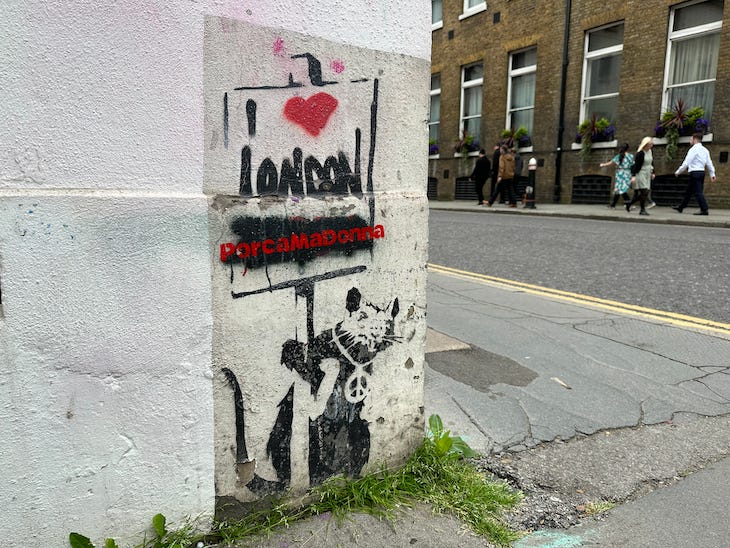 A banksy rat holds up a placard saying I heart London