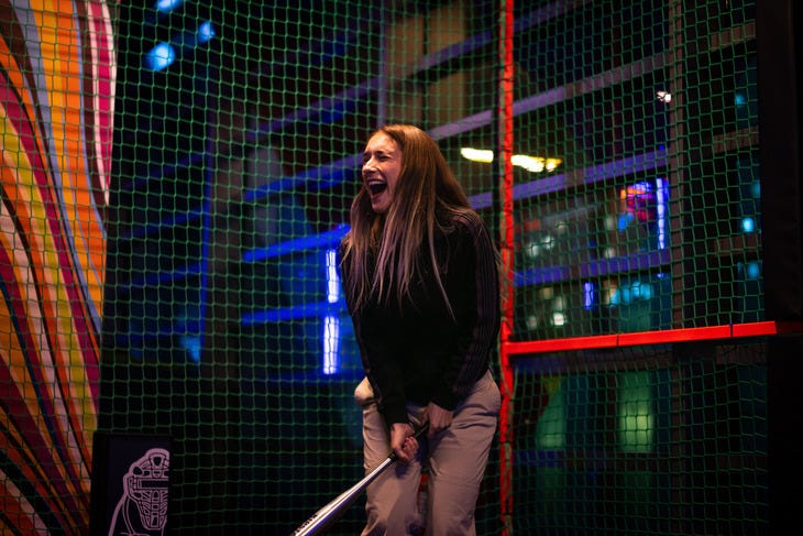 A lady with a baseball bat inside batting nets