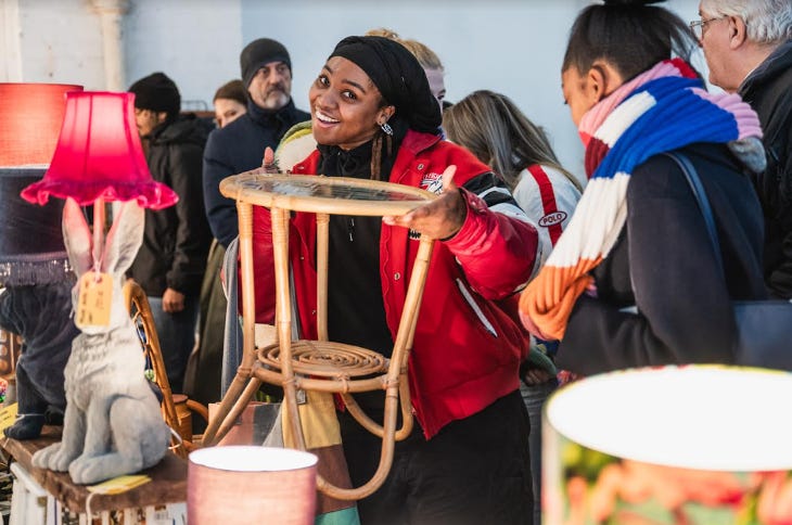 A woman posing with a small table at a flea market