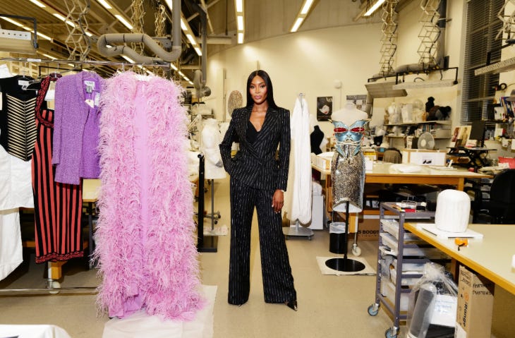 Naomi Campbell posing alongside a rail of clothes