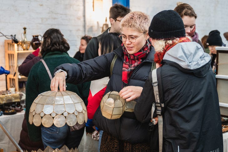 Two people examining a table lamp at Peckham Salvage Yard