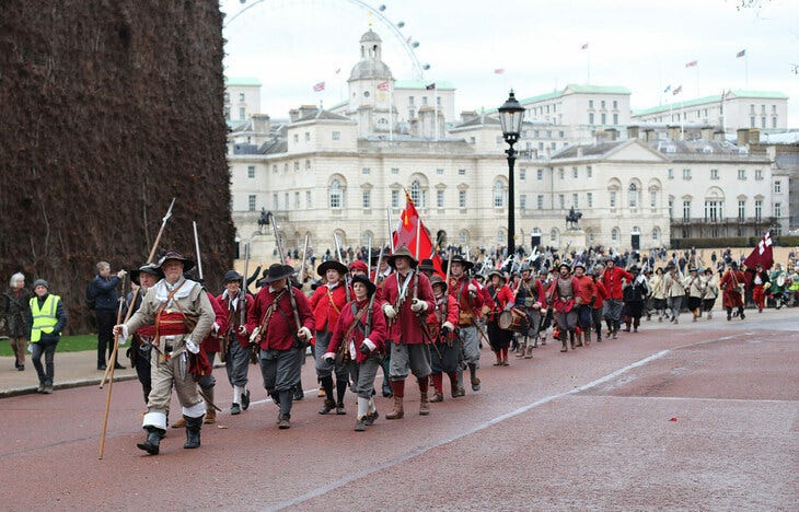 People in red royalist costumes marching past Horse Guards Parade