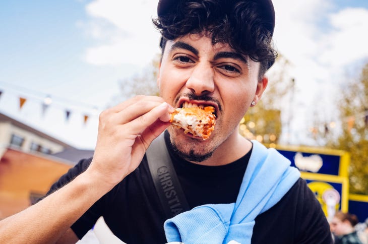 A man biting into a chicken wing