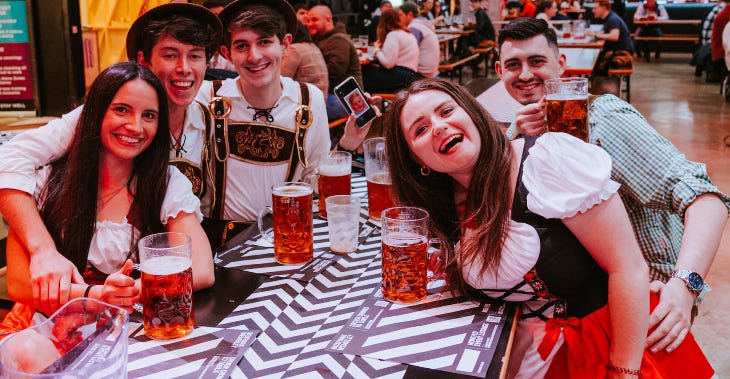 People dressed in Bavarian costumes sitting around a table at Oktoberfest