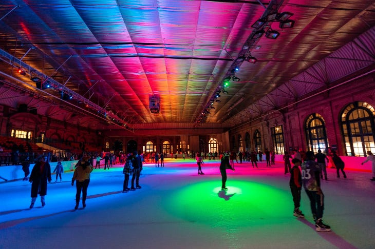 An indoor ice rink, lit with colourful lights