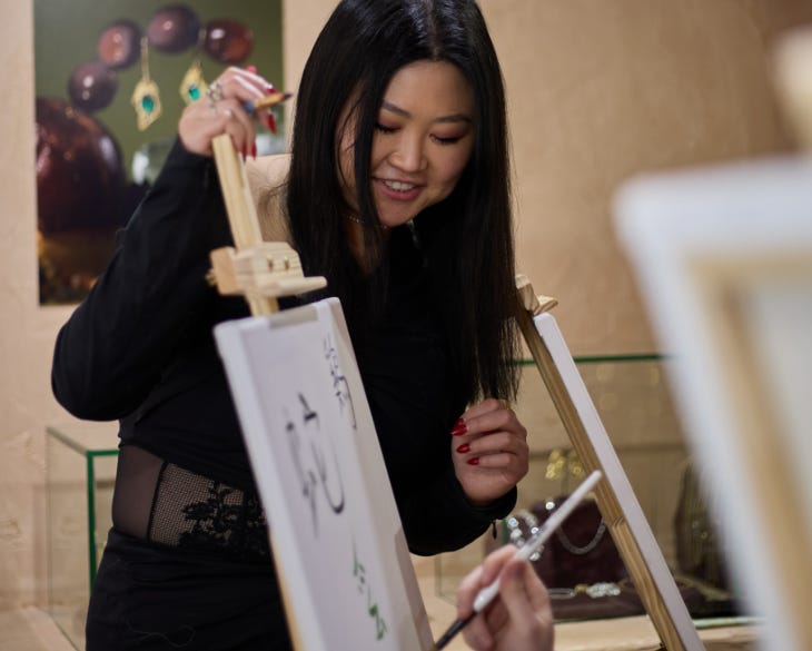 A teacher standing by an easel leading a calligraphy class