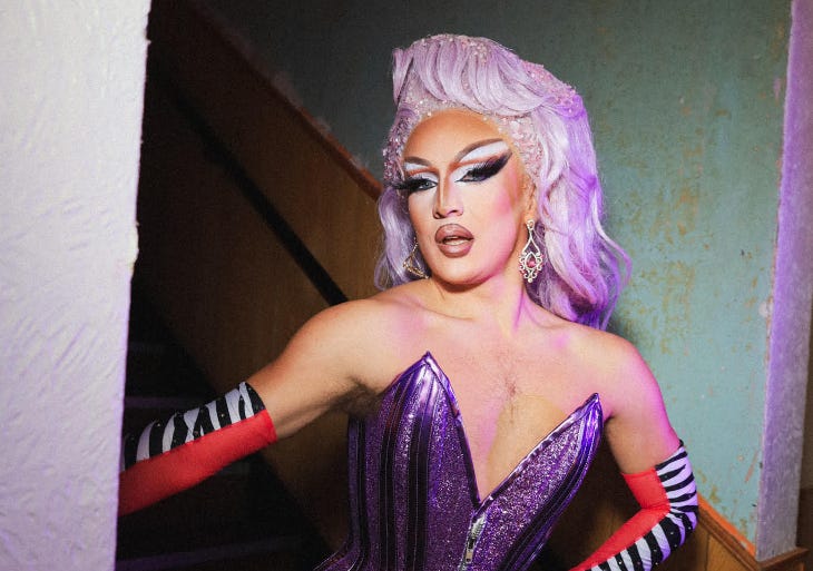 Drag queen Lucinda B-Hind in a purple glittery dress and zebra print gloves