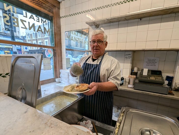 Manze's pie and mash Deptford: A man holding a plate of pie and mash