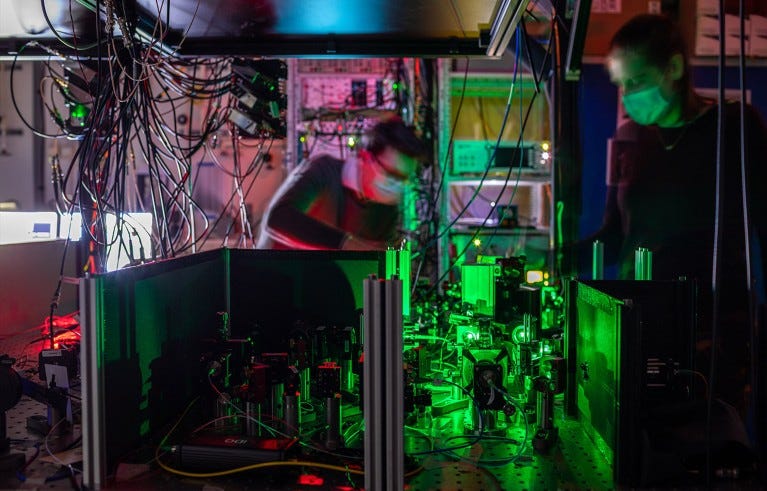 A pair of researchers work on one of the quantum network nodes, where mirrors and filters guide the laser beams to the diamond chip.