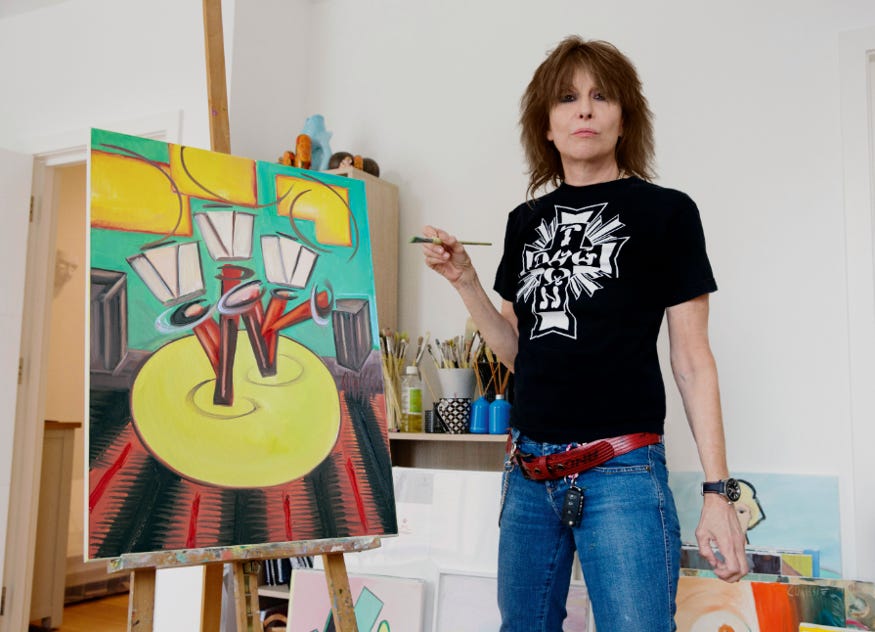 Chrissie Hynde posing next to one of her paintings