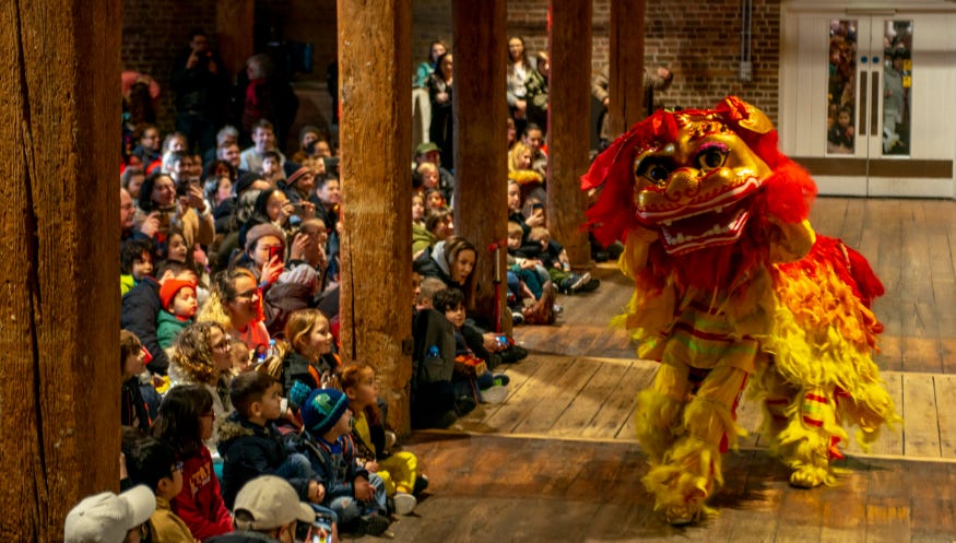 Crowds watching a traditional lion dance in the London Museum Docklands