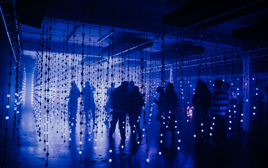 People wandering through a room illuminated blue