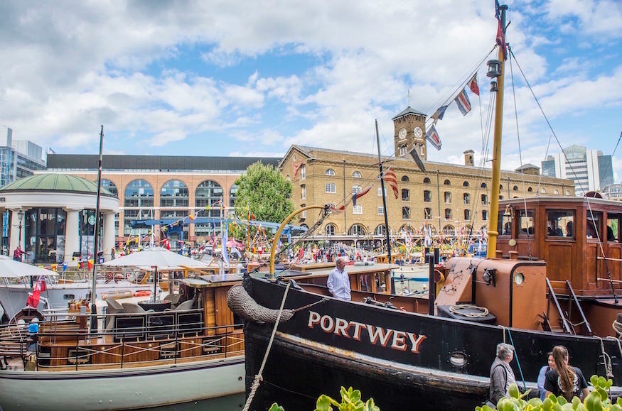 Classic boats moored up at St Katharine Docks, beneath colourful bunting