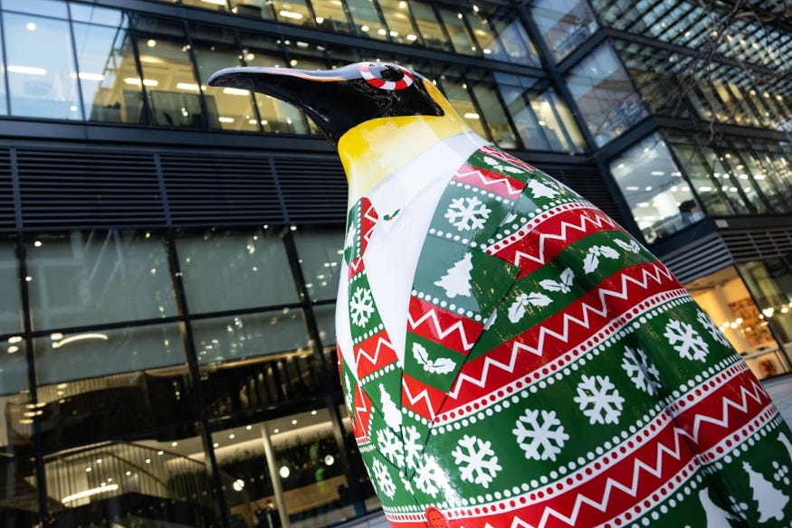 A penguin sculpture decorated with a red and green Christmas patterned jacket and tie