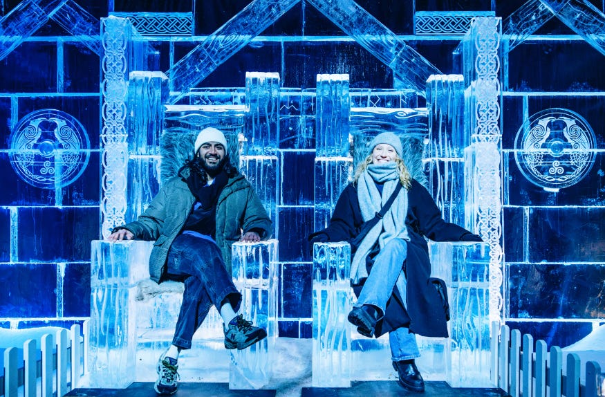 A couple sitting on thrones made from ice in the Ice Kingdom at Hyde Park Winter Wonderland