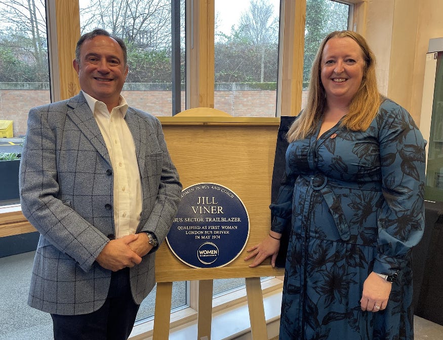 A lady and a man standing either side of a plaque to Jill Viner