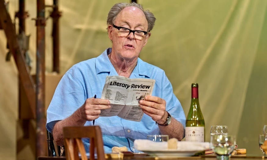 John Lithgow in a blue shirt reading the Literary Review, posing as author roald dahl
