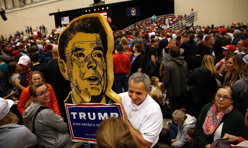 A foam cutout of Ronald Reagan sits atop a Trump campaign sign.