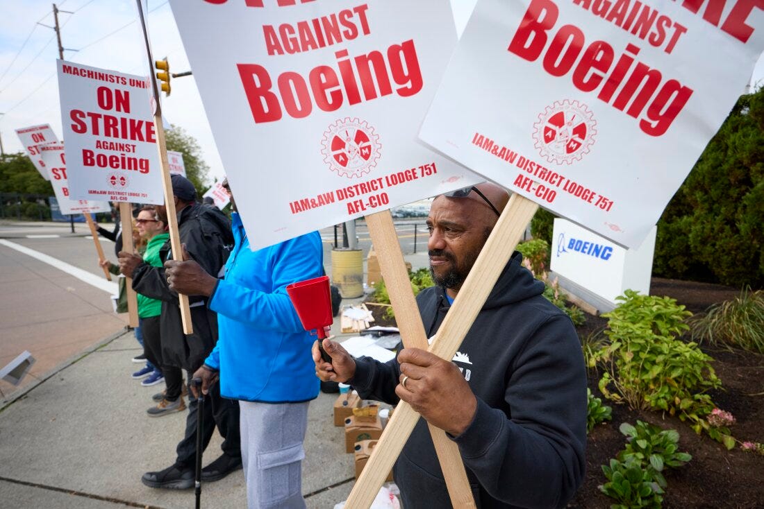 Boeing workers hold signs on the picket line at the Renton assembly plant on Friday in Renton, Wash.