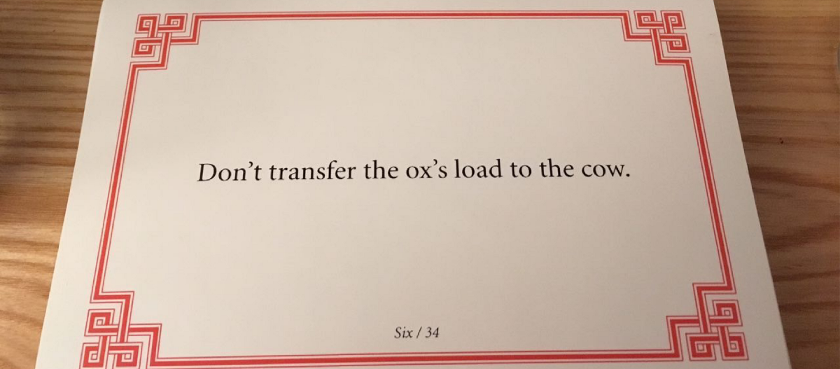 Photo of a lojong card with a red border. The text on the card reads: Don't transfer for ox's load to the cow.