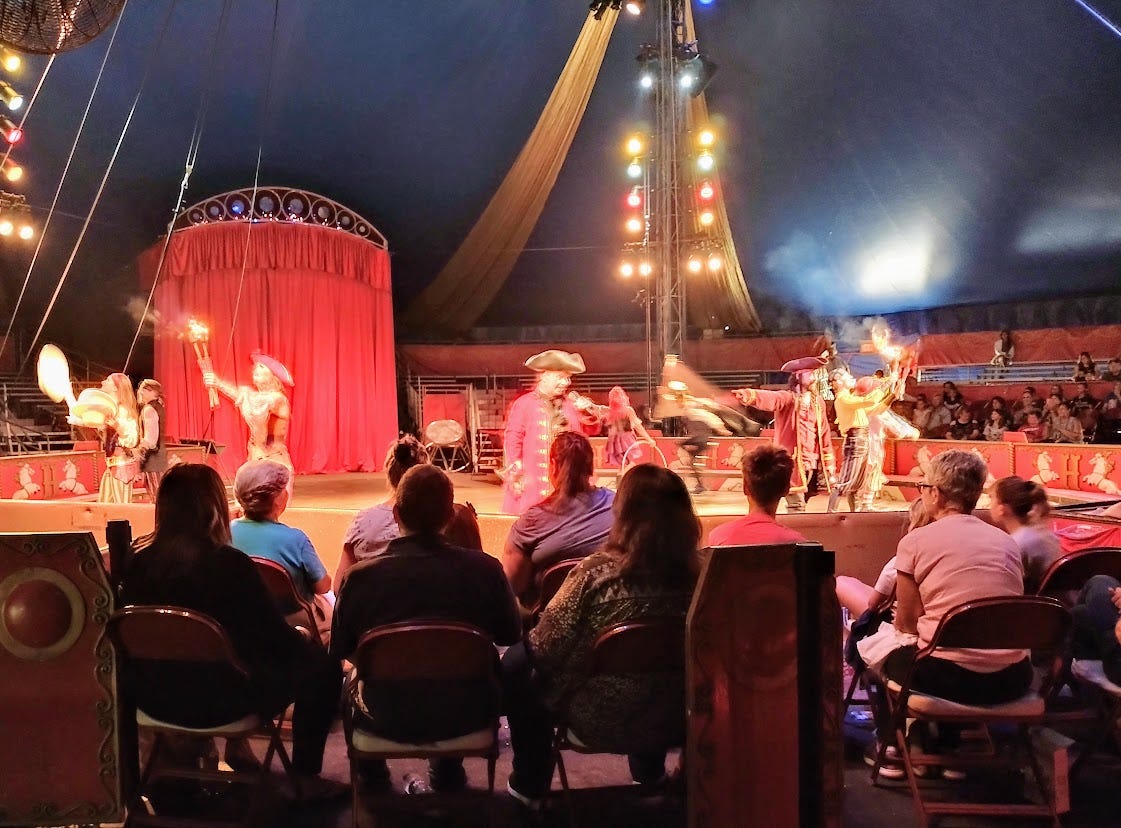 Performers in pirate dress in circus ring, including fire breathers