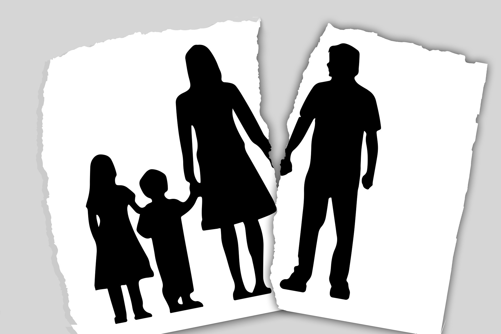 A silhouette of a family on a piece of paper with the husband torn away from the wife and children