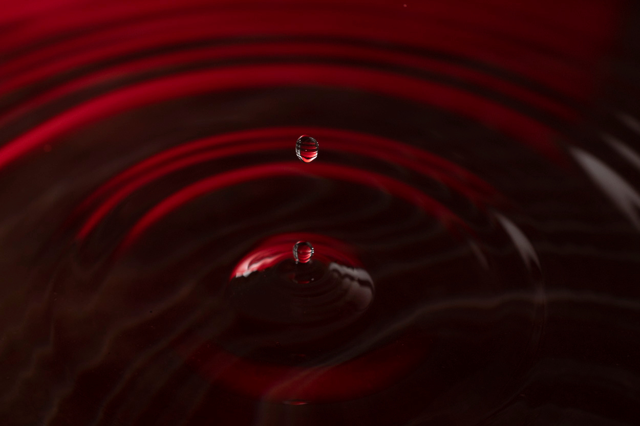 Water drops splashing into the concentric circles of the water and shot with a red gel tomake the water a deep red
