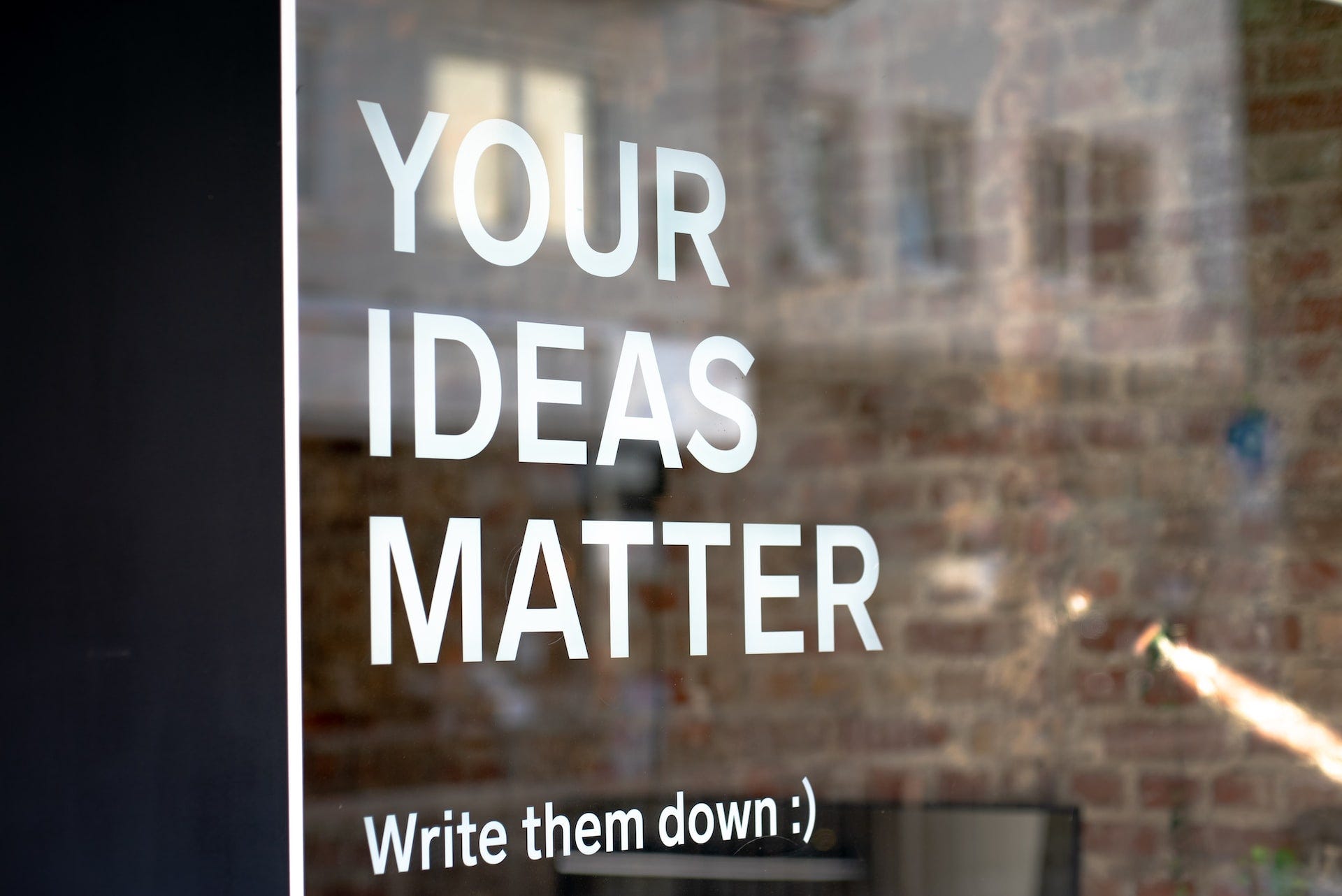 La vetrina di un locale in cui compare una scritta bianca: Your ideas matter, write them down :)