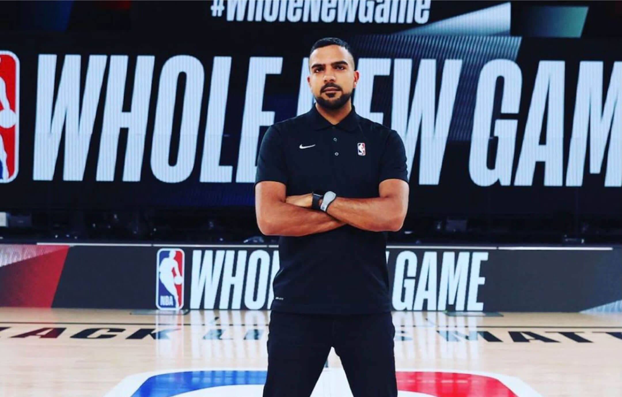 Three-quarter-length portrait of Gautam Kapur standing with his arms crossed on a basketball court