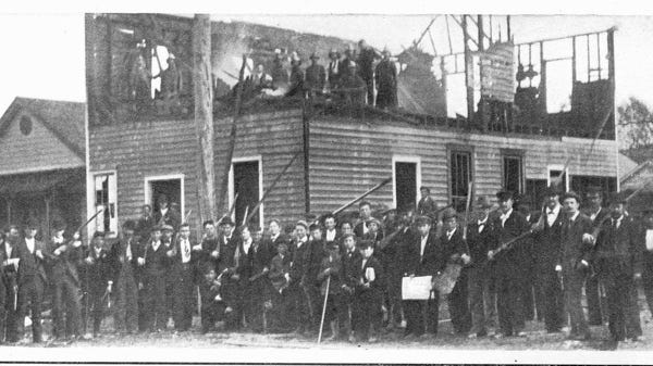 A mob stands outside the burnt offices of the Wilmington Daily Record