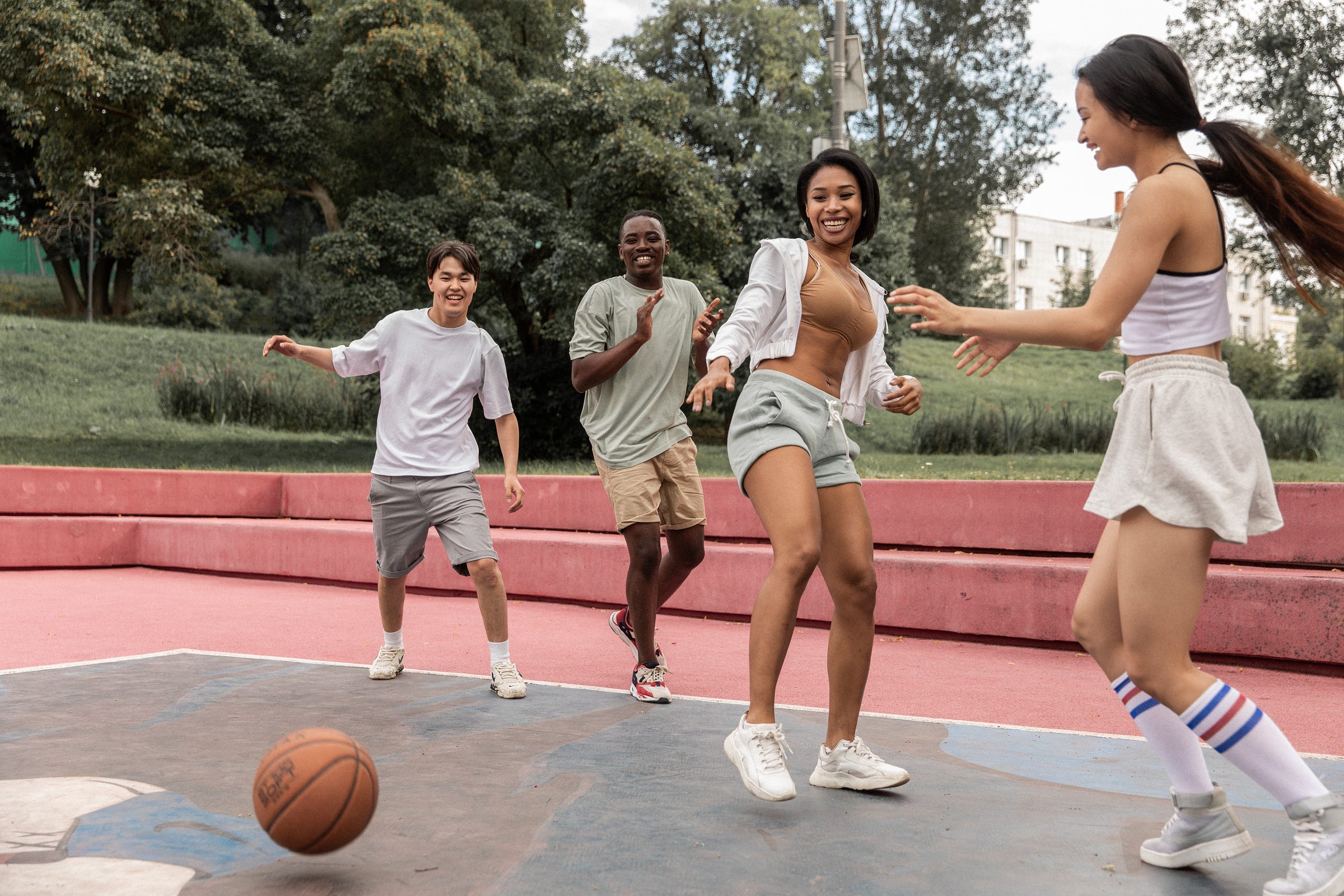 4 people playing sports in a park with a basketball on the floor