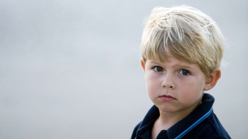 Photo of a young white boy with blonde hair, dark blue eyes, looking solemn